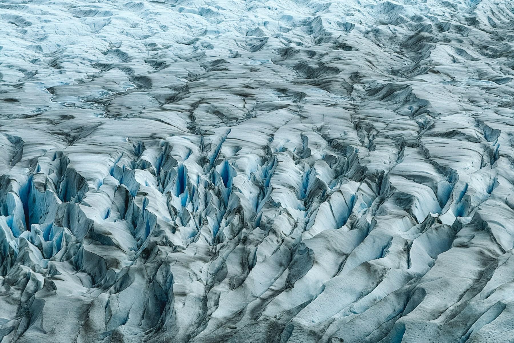 An aerial view of blue glacier ice winding through mountains