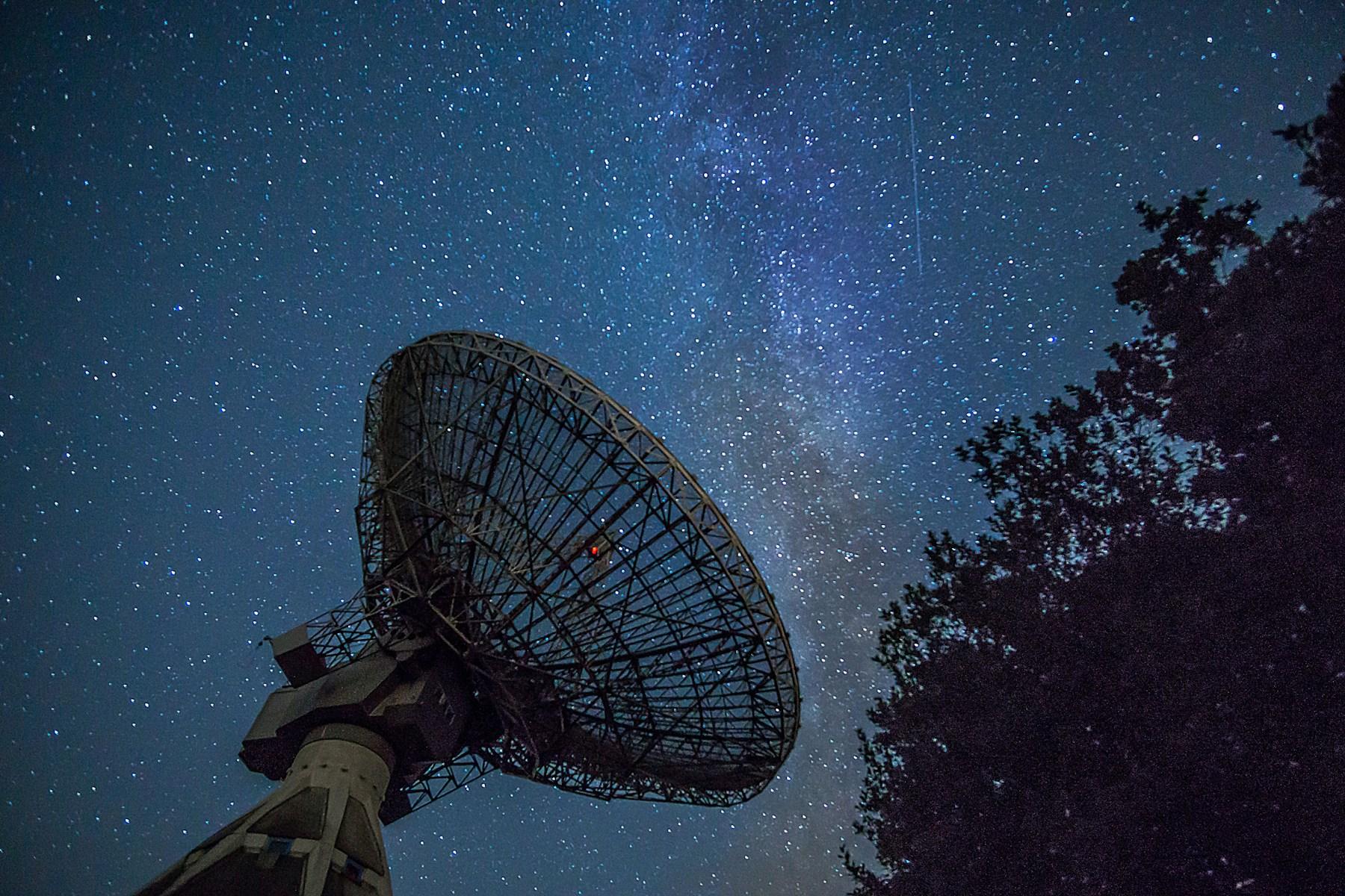A white observatory dish under a deep blue night sky